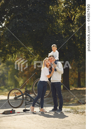 Family with son repare the bike in a park Family with son repare the bike in a park 64867490