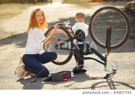 Mother with son repare the bike in a park Mother with son repare the bike in a park 64867591