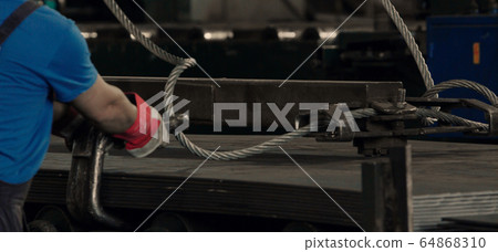 Worker installing big wire rope sling Worker installing big wire rope sling 64868310