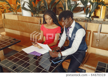 Stylish black couple sitting in a cafe and have business conversation 64870319