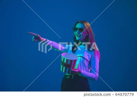 Caucasian woman's portrait isolated on blue studio background in pink-green neon light, stylish and beautiful, cinema concept Caucasian woman's portrait isolated on blue studio background in pink-green neon light, stylish and beautiful, cinema concept 64870779