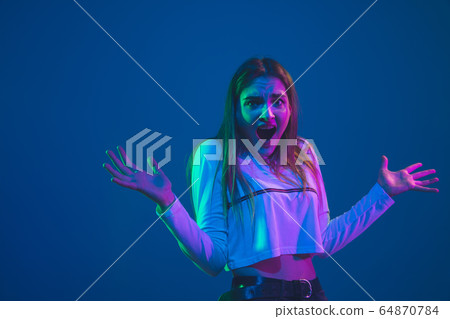 Caucasian woman's portrait isolated on blue studio background in pink-green neon light, stylish and beautiful Caucasian woman's portrait isolated on blue studio background in pink-green neon light, stylish and beautiful 64870784