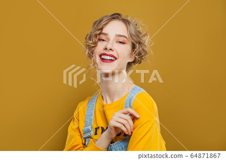 Happy smiling woman on bright yellow background 64871867