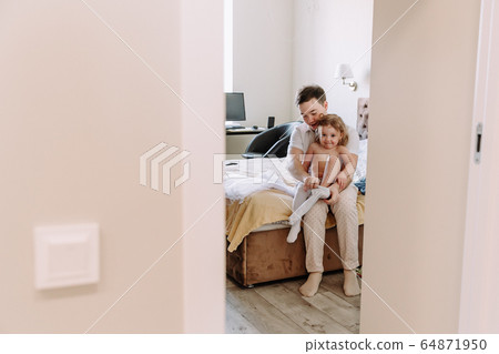 dad dresses his little daughter at home 64871950