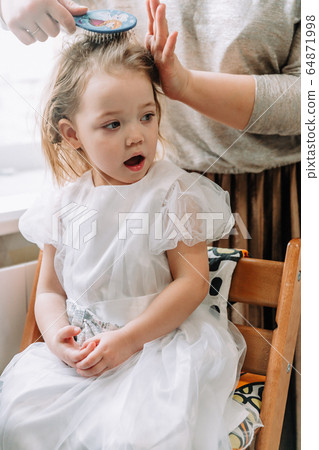 mother makes hair for her little daughter 64871998