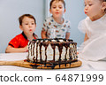 a little three-year-old girl blows out the candle on the cake 64871999