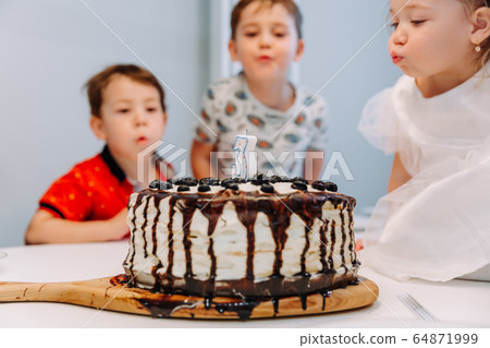 a little three-year-old girl blows out the candle on the cake a little three-year-old girl blows out the candle on the cake 64871999