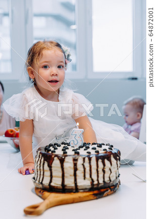 Portrait of cute little girl celebrating third birthday. 64872001