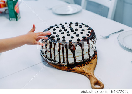first cake.the child takes the cake with his hand. hand in pastry cream. children's holiday 64872002