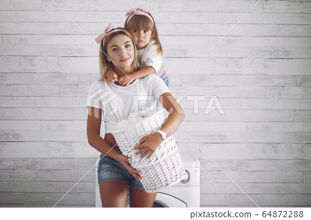 Mother and daughter in a bathroom near wash mashine 64872288