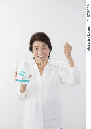 Senior woman with mouthwash 8020 exercise 64872669