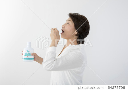 Senior woman with mouthwash 8020 exercise 64872706