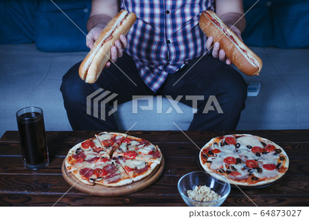 Overweight man with big amount of junk food 64873027