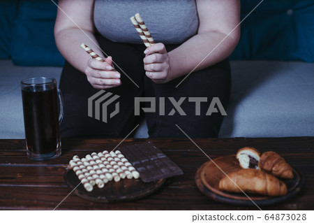 Lonely woman eating sweets and watching tv 64873028