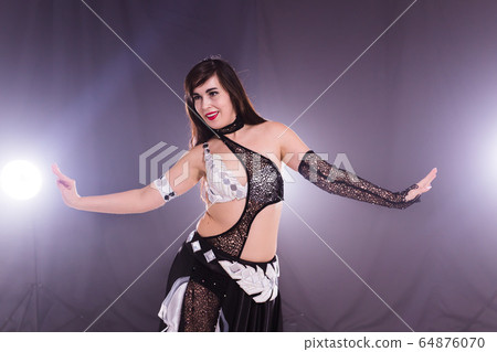 Young woman belly dancer in exotic dress with gold, dancing tribal fusion dance in studio. 64876070