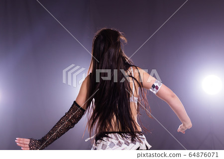 Spirituality dance. Beautiful sexy woman with luxury glossy eastern make-up dancing tribal fusion. Belly dance. Back view. 64876071