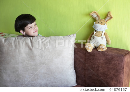 Boy at home with bunny in face mask symbolizing coronavirus quarantine. Boy at home with bunny in face mask symbolizing coronavirus quarantine. 64876167