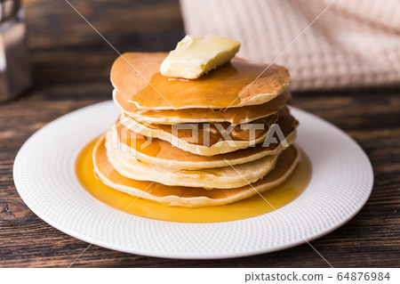 Golden pancakes with butter and warm maple syrup. Golden pancakes with butter and warm maple syrup. 64876984