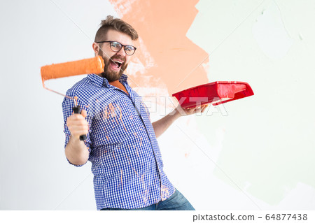 Funny man with painting roller indoors. Redecoration, renovation, apartment repair and refreshment concept. Funny man with painting roller indoors. Redecoration, renovation, apartment repair and refreshment concept. 64877438
