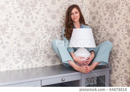 Girl sitting on chest of drawers at home. Quarantine, isolation, coronavirus pandemic world. Stay at home. 64878818