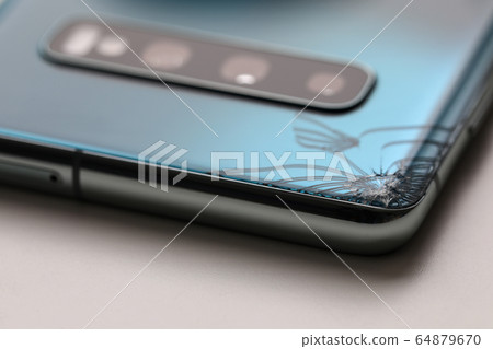 Modern smartphone lying at table with crack in corner 64879670
