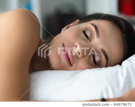 Beautiful woman calmly sleeping in her bed Beautiful woman calmly sleeping in her bed 64879672