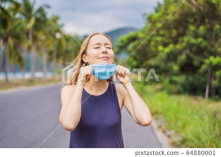 Quarantine is over concept. Woman taking off mask outdoor. We are safe. Coronavirus ended. We won Quarantine is over concept. Woman taking off mask outdoor. We are safe. Coronavirus ended. We won 64880001