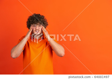 Caucasian young man's monochrome portrait on orange studio background 64881497