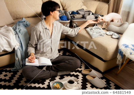 Open grey suitcase with different clothes packed for journey at home. Nordic style minimalism. woman packing bags for holidays and preparing things for vacations getting ready for travel Open grey suitcase with different clothes packed for journey at home. Nordic style minimalism. woman packing bags for holidays and preparing things for vacations getting ready for travel 64881549