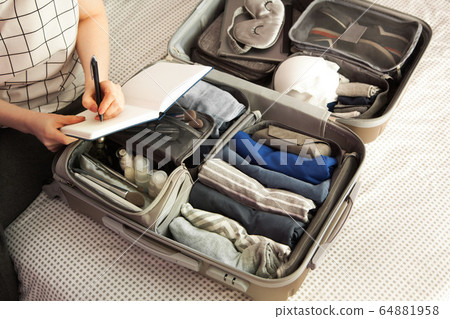 Open grey suitcase with different clothes packed for journey at home. Nordic style minimalism. woman packing bags for holidays and preparing things for vacations getting ready for travel 64881958