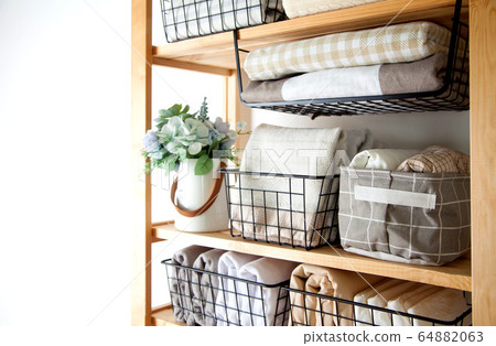 Bed sheets, duvet covers and towels are folded vertically. Metal and fabric black baskets. The concept of housework and storage. Bed sheets, duvet covers and towels are folded vertically. Metal and fabric black baskets. The concept of housework and storage. 64882063
