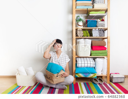 Bed sheets, duvet covers and towels are folded vertically. Metal and fabric black baskets. Bedclothes bright colors. 64882368