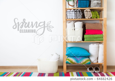 Bed sheets, duvet covers and towels are folded vertically. Metal and fabric black baskets. Bedclothes bright colors. Bed sheets, duvet covers and towels are folded vertically. Metal and fabric black baskets. Bedclothes bright colors. 64882426