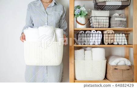 Bed sheets, duvet covers and towels are folded vertically. Metal and fabric black baskets. The concept of housework and storage. 64882429