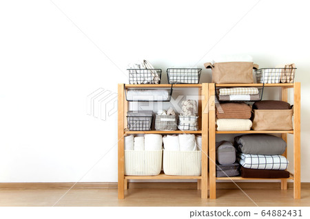Bed sheets, duvet covers and towels are folded vertically. Metal and fabric black baskets. The concept of housework and storage. 64882431