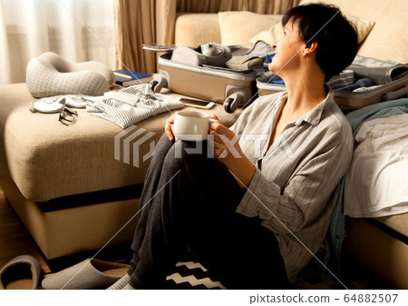 Open grey suitcase with different clothes packed for journey at home. Nordic style minimalism. woman packing bags for holidays and preparing things for vacations getting ready for travel 64882507