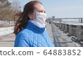 A girl in a protective mask on the street. Prevention and protection of health and safety of life. 64883852