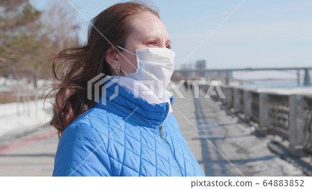A girl in a protective mask on the street. Prevention and protection of health and safety of life. 64883852