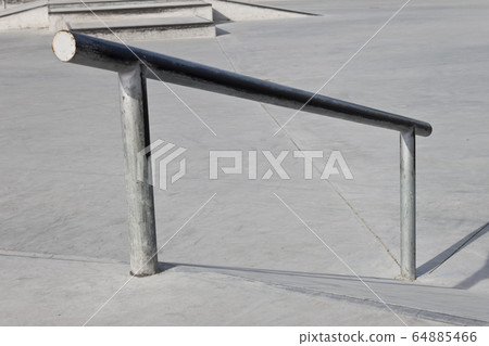 Sloped metal rail for grind tricks in an empty Sloped metal rail for grind tricks in an empty 64885466