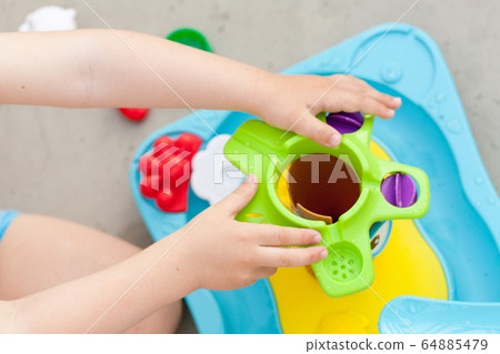 Child's hand playing with water game, car, star, boat 64885479