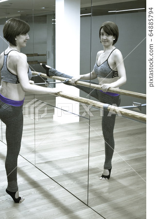 Female dancer doing stretching on the ballet barre 64885794