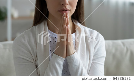 Close up of young woman praying at home 64886181