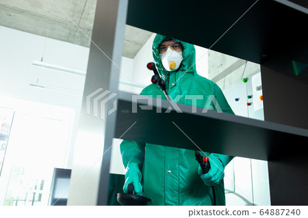 Experienced specialist disinfecting frequently touched surfaces indoors 64887240