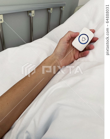 Female patient holding nurse call button in hospital room 64888031