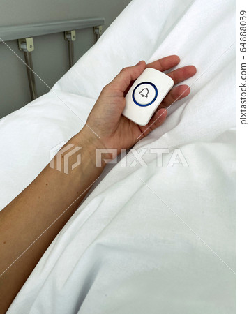 Young lady hand holding nurse call button in hospital room Young lady hand holding nurse call button in hospital room 64888039