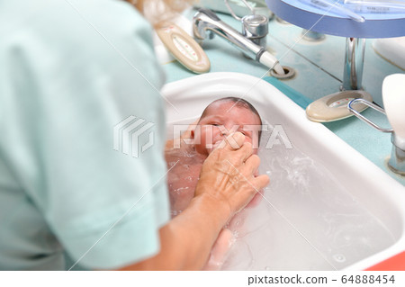 A nurse gives the first bath of a newborn boy 64888454