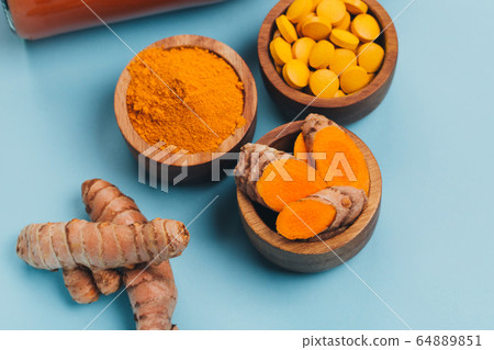 Turmeric in different conditions: fresh, dry root, pills, powder and cut plant. 64889851