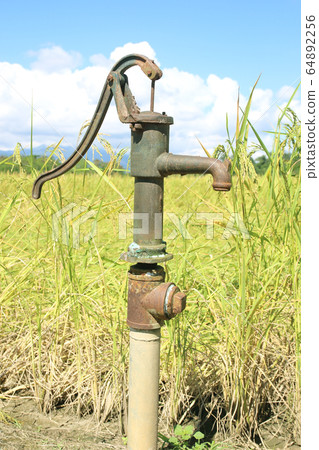 Hand pump leading to an artesian well. Pumping 64892256