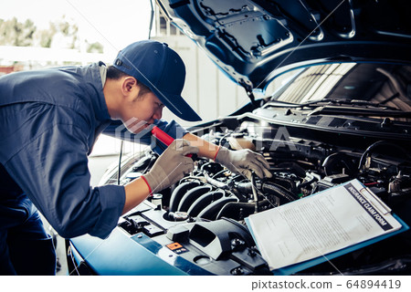 Car mechanic technician holding flashlight 64894419