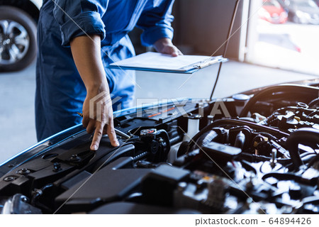 Car mechanic holding clipboard and checking to 64894426